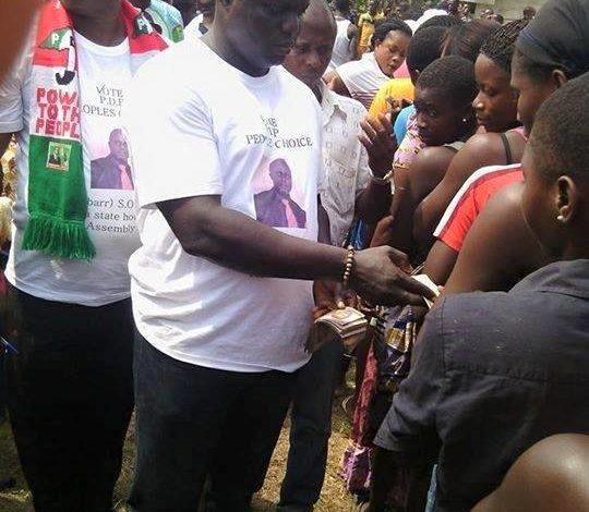 A Nigerian voter casting a ballot while election officials monitor proceedings, illustrating the importance of free and fair elections.
